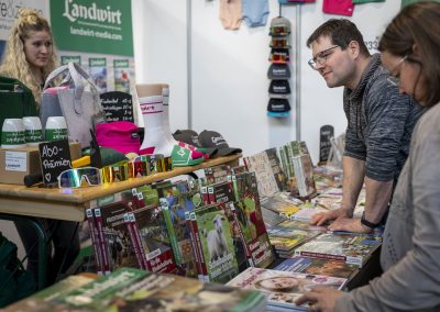 Besucher am Stand von Landwirt Medien, schauen sich Magazine und Bücher an