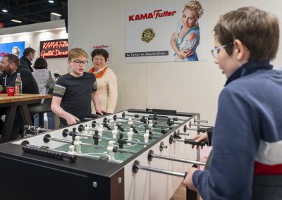 Zwei Kinder spielen Kicker am Kama-Futter Stand