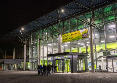 Der Haupteingang der Messe Augsburg abends grün beleuchtet
